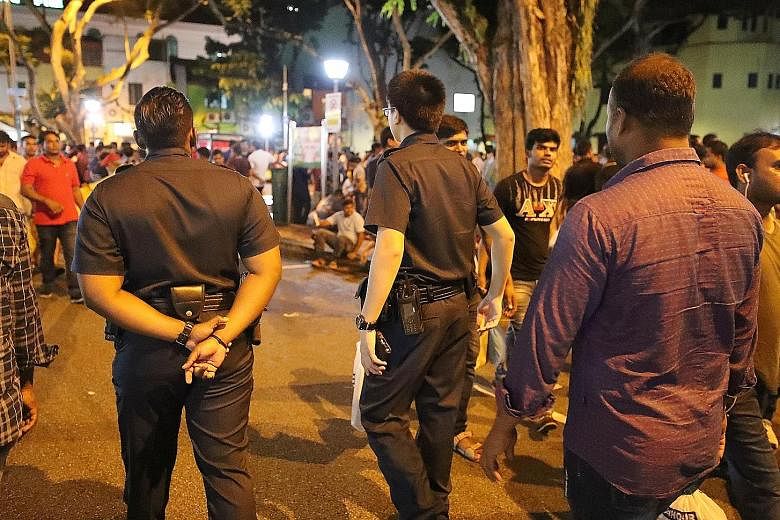 Police officers patrolling Desker Road in the evening. The area is still popular with migrant workers on Sundays, although the crowds are smaller than before, according to shopkeepers and migrant workers. 