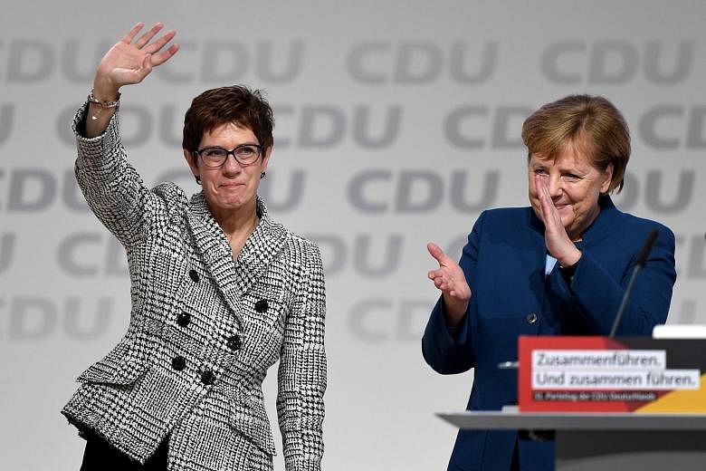 An elated Annegret Kramp-Karrenbauer waving next to German Chancellor Angela Merkel after being elected as the party leader during the Christian Democratic Union party congress in Hamburg, Germany, yesterday.