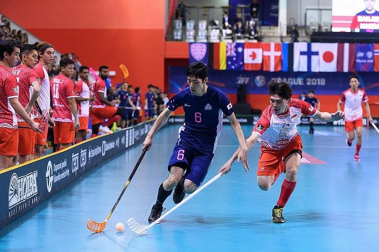 Nicholas Chua (right) and Rikiya Matsumoto tussling for the ball in Singapore's 4-2 loss to Japan yesterday in the play-off for 15th at the World Floorball Championship.
