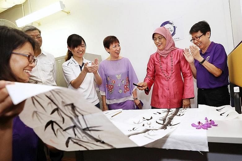 President Halimah Yacob adding two leaves to a Chinese painting at the official opening of Brahm Centre @ MacPherson yesterday. With her are (from right) the centre's counselling and care manager Lily Tan, Brahm Centre founder Angie Chew and MacPhers