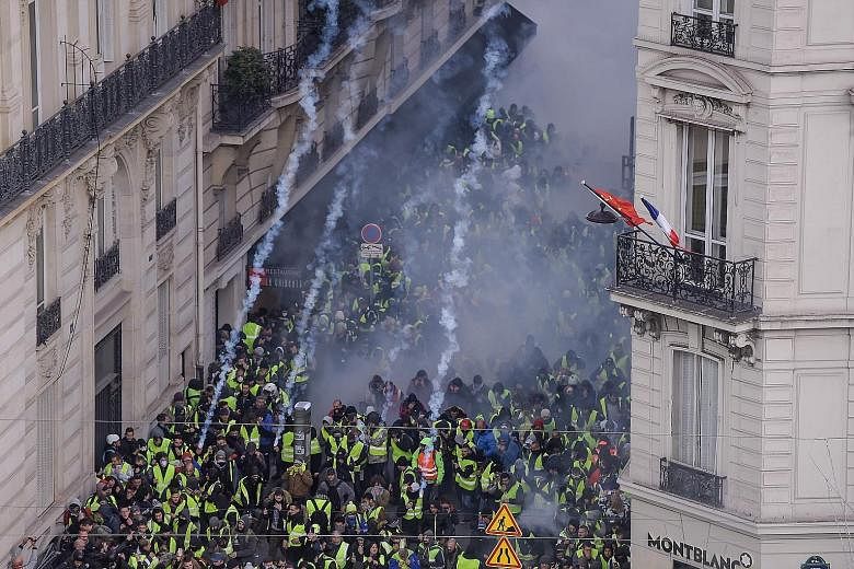 Protesters clashing with riot police as tear gas filled the air on the Champs-Elysees in Paris yesterday. An estimated 31,000 people had joined the protests, Deputy Interior Minister Laurent Nunez said.