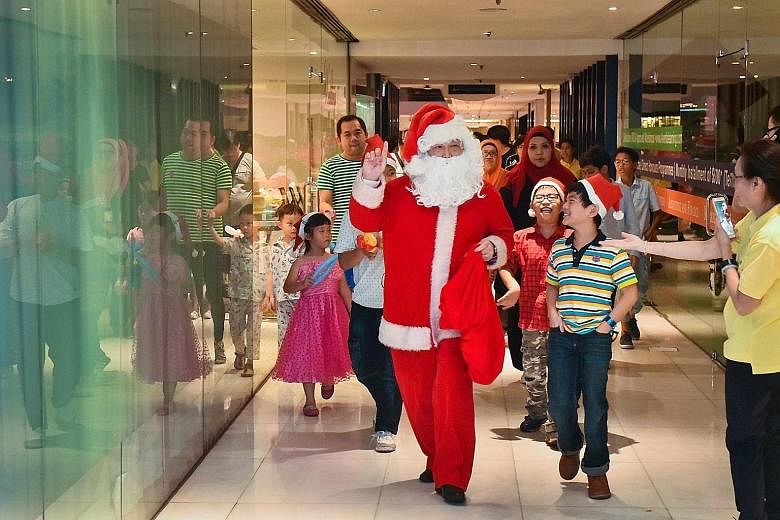 Concorde Hotel Singapore's catering sales director Kenneth Looi, 58, dressing up as Santa Claus to entertain the beneficiaries of The Straits Times School Pocket Money Fund (STSPMF). The hotel organised a Christmas light-up and party to mark its 10th