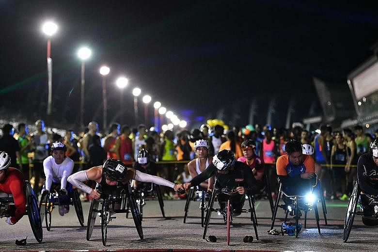 Two elite wheelchair athletes wishing each other well as they line up at the start in front of the main marathon participants.