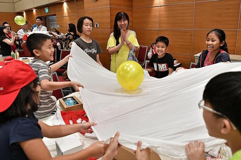 Singapore Press Holdings staff volunteer Florence Ong, 50, with children from the Life Community Services Society during a game at the party yesterday. SPH staff and management contributed gifts worth an estimated $20,000 and granted about 300 wishes