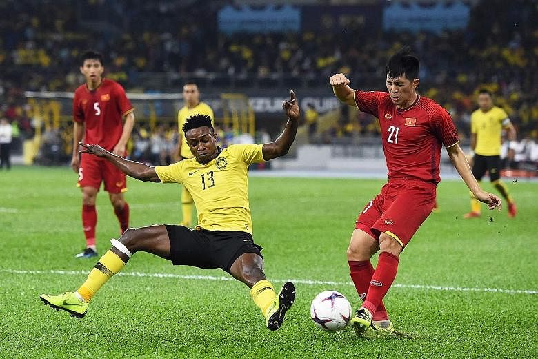 Malaysia's Mohamadou Sumareh (left) attempting to stop Vietnam defender Tran Dinh Trong during the first leg of the Suzuki Cup final yesterday at the Bukit Jalil National Stadium in Kuala Lumpur.