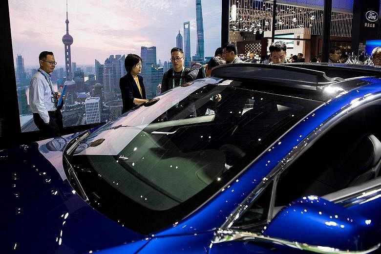 Visitors looking at a Model S car by Tesla Motors during the first China International Import Expo in Shanghai last month. China is reported to be moving towards cutting its trade-war tariffs on US-made cars. Shares of carmakers, including Daimler, F