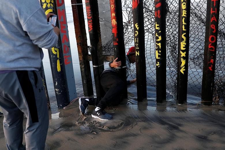 A migrant, who was part of a caravan of thousands from Central America trying to reach the United States, crawling through a gap in the border wall to cross illegally from Mexico's Tijuana to the US on Thursday. On the same day, The Washington Post r