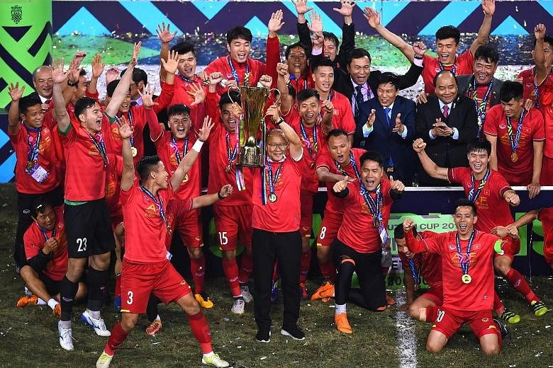 Vietnam's coach Park Hang-seo (centre) holding the trophy as the players and Vietnamese Prime Minister Nguyen Xuan Phuc (second from right in black suit) celebrate after winning the AFF Suzuki Cup last night. Vietnam defeated Malaysia 1-0 (3-2 on agg