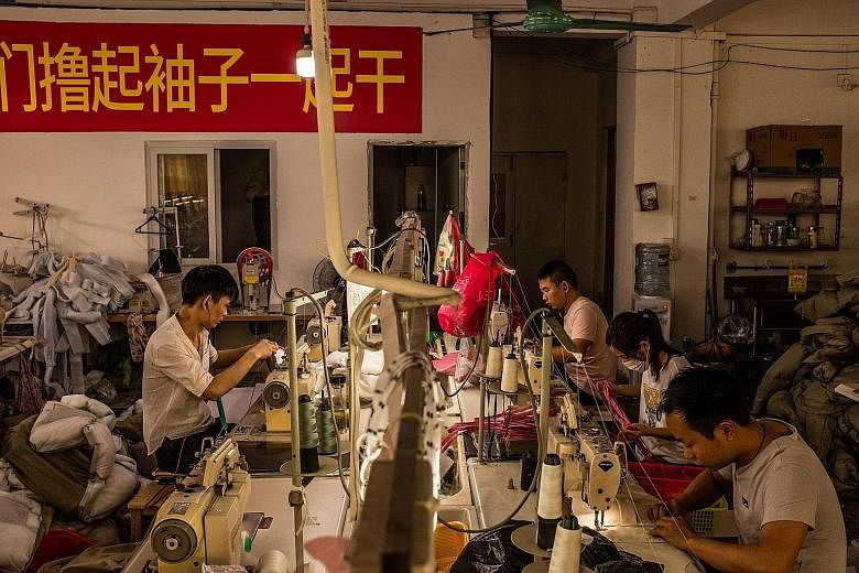Employees from a garment factory in Guangzhou sitting behind handwritten signs that say in Chinese, ''Looking for customers". As China's economy slows sharply, factories such as this one (above) in Dongguan, Guangdong province, are closing. And they 