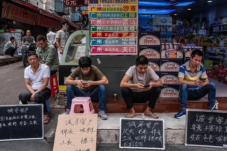 Employees from a garment factory in Guangzhou sitting behind handwritten signs that say in Chinese, ''Looking for customers". As China's economy slows sharply, factories such as this one (above) in Dongguan, Guangdong province, are closing. And they 