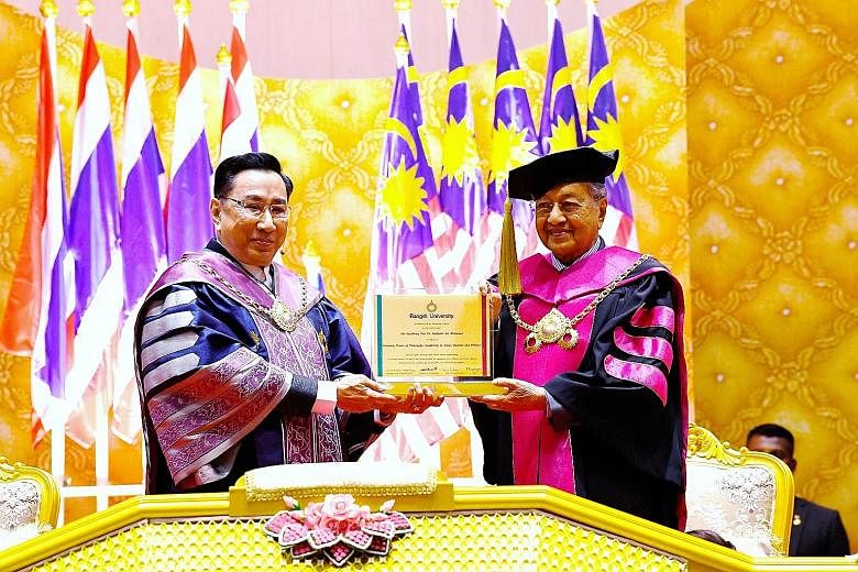 Malaysian Prime Minister Mahathir Mohamad receiving an honorary doctorate degree in social leadership, entrepreneurship and politics yesterday from Dr Arthit Ou Rairat (far left), president of Thailand's Rangsit University.