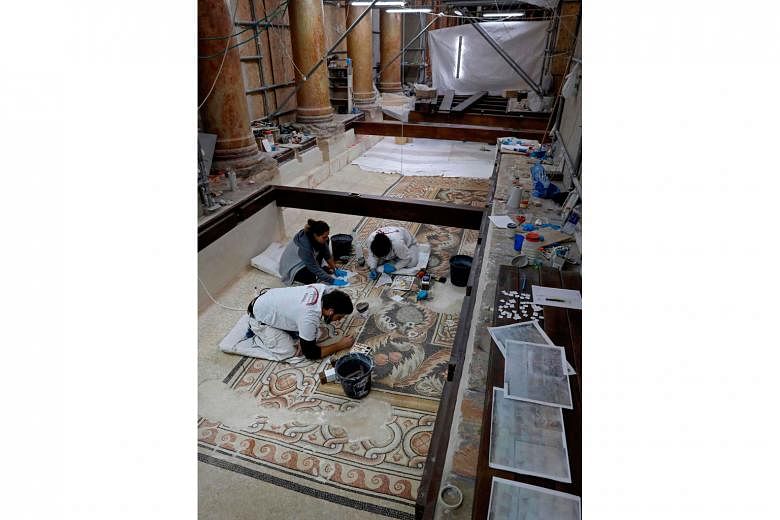 Italian artists cleaning and restoring pebble mosaics at the church's nave last month.