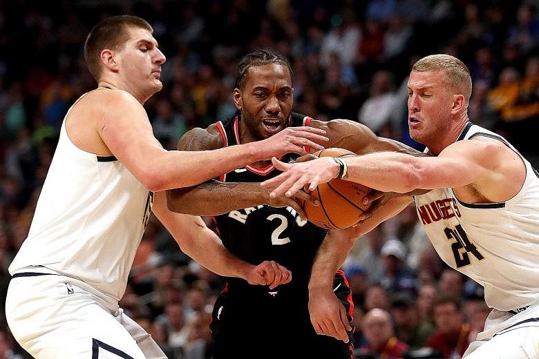 The Toronto Raptors' Kawhi Leonard is closely marked by the Denver Nuggets' Nikola Jokic (left) and Mason Plumlee while driving to the basket in the first quarter of Denver's 95-86 home win on Sunday. Victory over the league-leading Raptors helped th