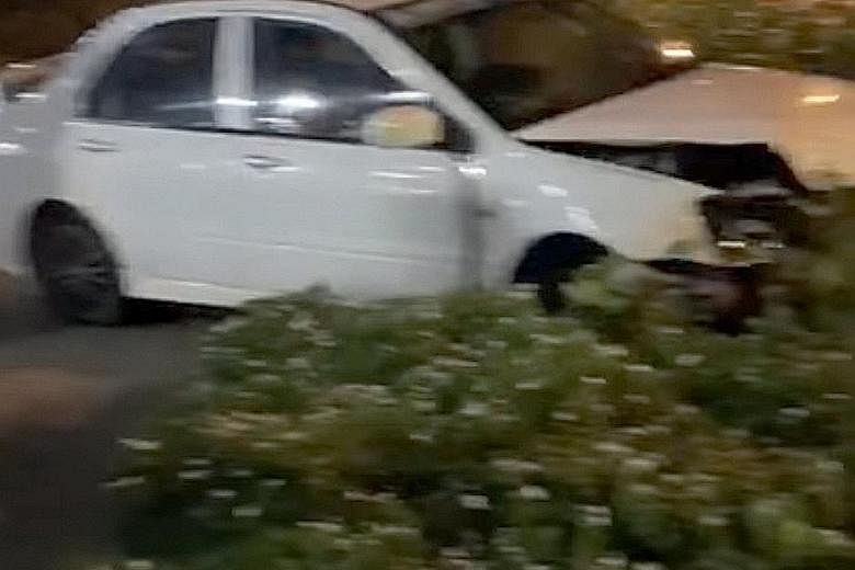 A photo from a video showing the white car on the grass and bushes next to the road. The teenage driver, who does not have a licence, has been arrested.
