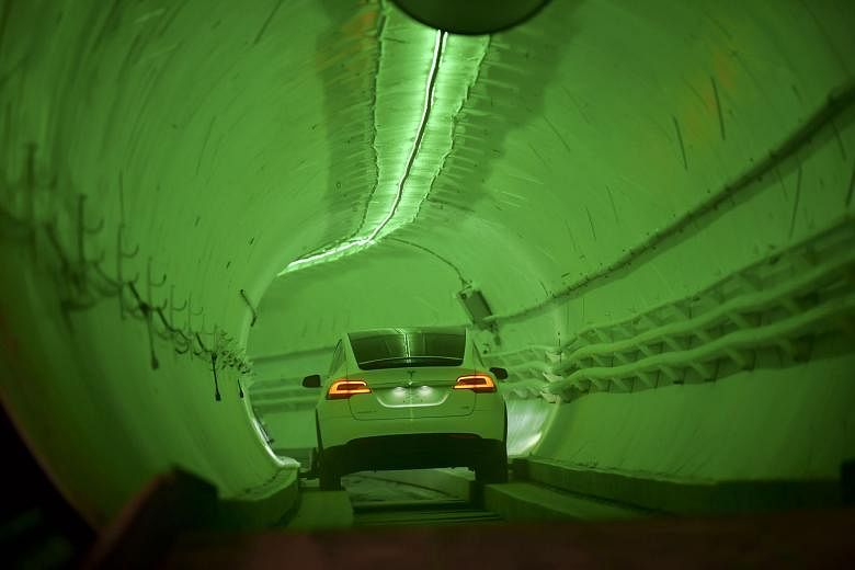 Tesla chief executive officer Elon Musk (above) unveiling the first completed tunnel by his company Boring Company in Hawthorne, California, on Tuesday, with a modified Tesla Model X driving into the tunnel at the event (left).