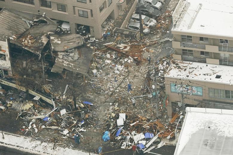 This aerial view shows workers inspecting the site of the collapsed and charred building in Sapporo, northern Japan, where a large explosion occurred, injuring 42 people. The force of the explosion shattered glass windows in at least 20 buildings, so