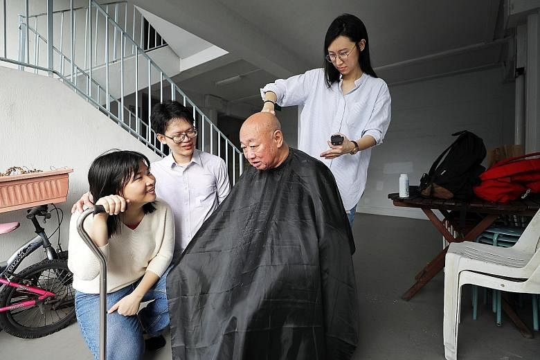 Ms Poh Chu Yin giving Mr Yeo Yeo Hong a haircut outside his flat, as volunteers Abraham Yeo and Peng Chengyu, 23, a nurse, talk to the 76-year-old retiree.