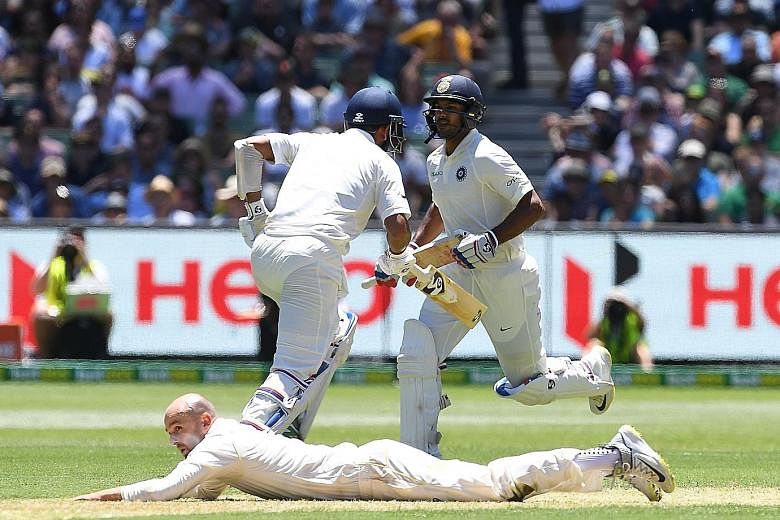 Indian batsmen Cheteshwar Pujara (left) and Mayank Agarwal running between the wickets as Australian fielder Nathan Lyon misses a catch on day one of the Boxing Day Test match at the MCG yesterday. The four-match series is tied 1-1.