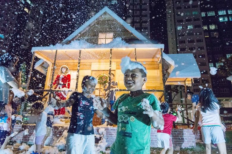 Children playing with snow foam (above) from snow machines that carpenter Tan Koon Tat installed together with the 4.5m-tall log cabin (below) he built in front of Block 178 Woodlands Street 13. Mr Tan said he built the log cabin using materials sour