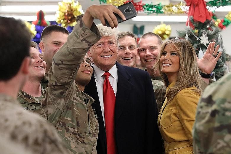 US President Donald Trump and his wife Melania posing for a wefie with US soldiers during a surprise visit to the Al Asad Air Base in Iraq on Wednesday. About 100 US servicemen and women, some of whom were wearing red "Make America Great Again" caps,