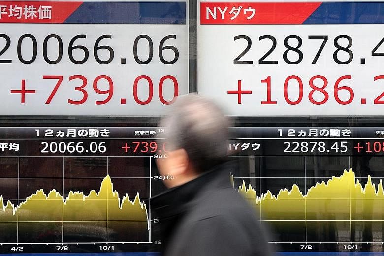 A stock market indicator board showing the Nikkei 225 Stock Average (left) and the New York Dow Jones in Tokyo yesterday. The Dow's rebound helped pull Japan's index out of the bear market it had entered earlier this week, with the Nikkei up nearly 4