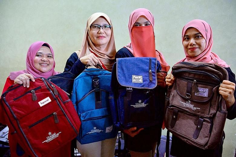 Parti Pribumi Bersatu Malaysia workers showing the different Herschel backpacks - with the party logo emblazoned on them - given to select central delegates at the party's annual general assembly in Putrajaya yesterday.