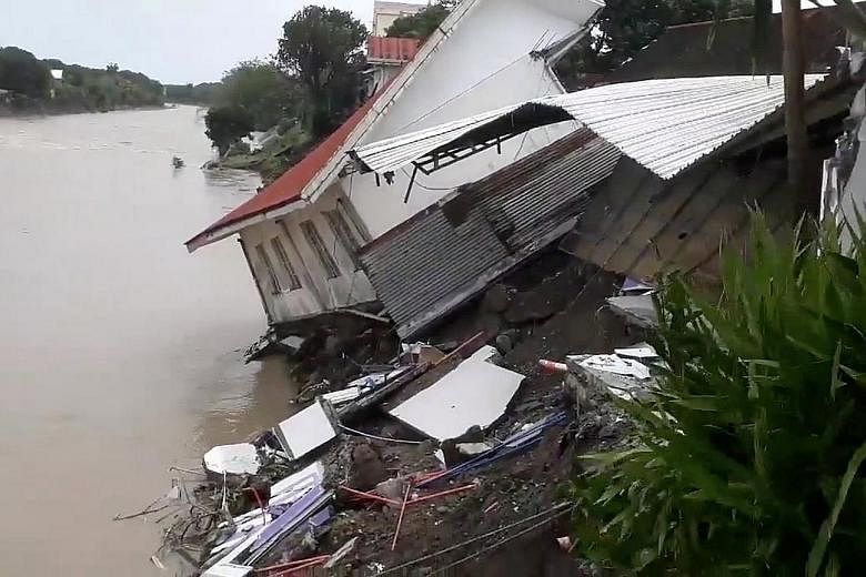 People wading through a flooded street yesterday in the town of Baao in Camarines Sur province, where casualties from the weekend storm included a father and his son, who were buried alive in a landslide. A destroyed house in Daet, in Luzon's Camarin
