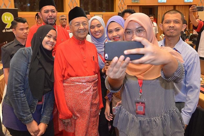 Members of the Malaysian media taking a wefie with PPBM chairman Mahathir Mohamad when he visited the media centre at his party's annual assembly yesterday.