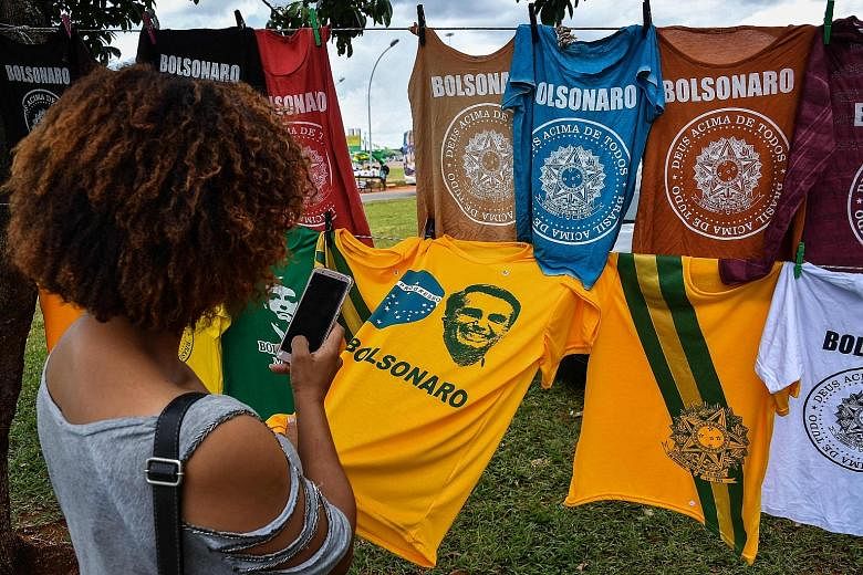 T-shirts with the image of new Brazilian President Jair Bolsonaro on display for sale in Brasilia. Inaugurated yesterday, Mr Bolsonaro has vowed to eradicate graft, crack down on crime and open up Brazil's protectionist economy to the free market.