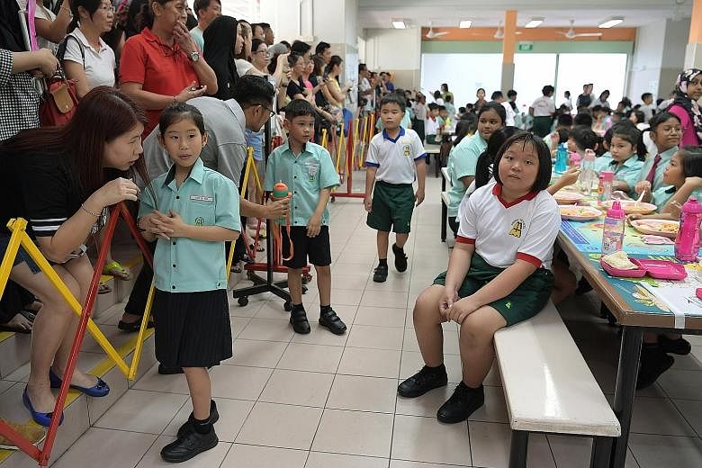 Education Minister Ong Ye Kung chatting with Primary 1 pupils on their first day of school at Huamin Primary yesterday. At the school, he launched mobile app Parents Gateway, which aims to improve communication between parents and schools at the prim