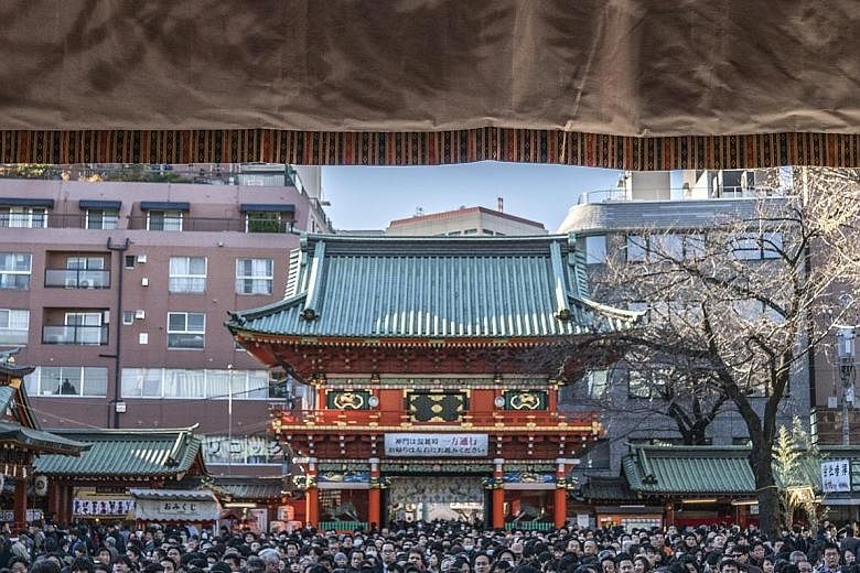 People offering prayers on the first business day of the year at the Kanda Myojin shrine in Tokyo, Japan, yesterday. Japan's benchmark bond yield fell to the lowest in more than two years as a stronger yen and a slowdown in global manufacturing spurr