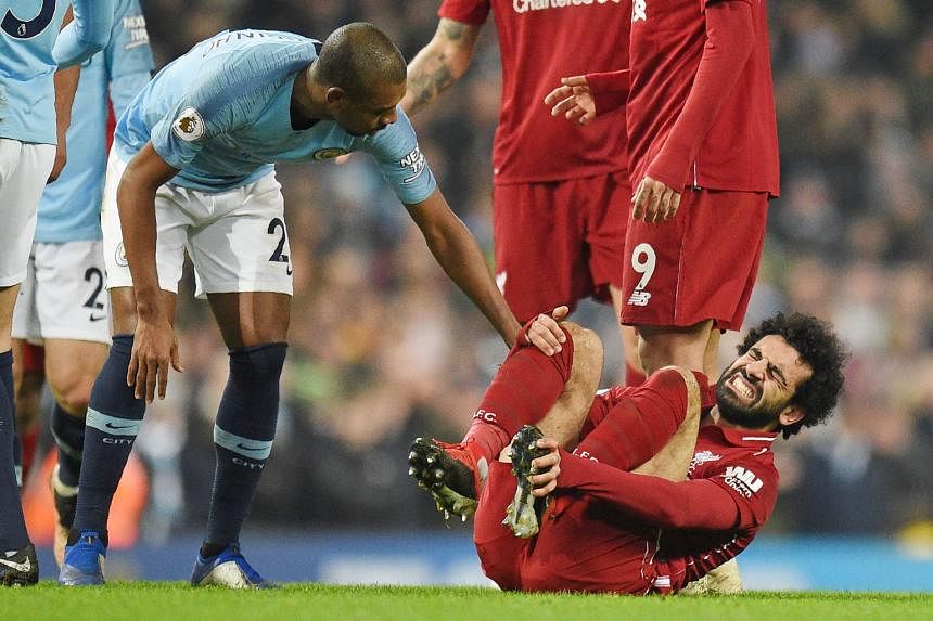 Above: Manchester City defender John Stones making a last-ditch tackle to keep the ball out of his goal by 1.12cm and away from Liverpool's Mohamed Salah. Far left: Salah grimacing after being felled by a tackle by City captain Vincent Kompany as a c