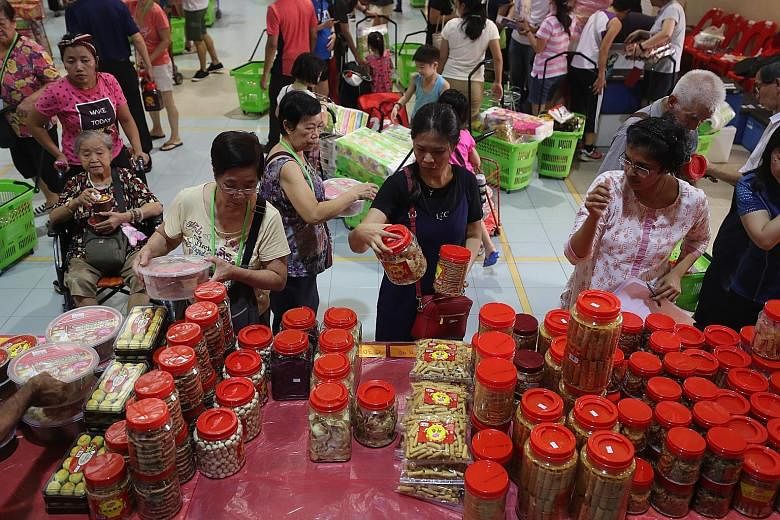 Shoppers choosing tidbits at Henderson Community Club yesterday, as they got to stock up early on groceries and goodies for the Chinese New Year. Volunteers turned an empty hall into a marketplace for 170 low-to middle-income families who may not qua