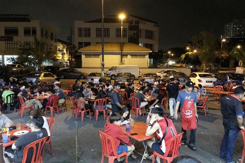 Customers smoking by the roadside outside a Kuala Lumpur mamak restaurant, beyond the stipulated 3m from the roofed eatery.
