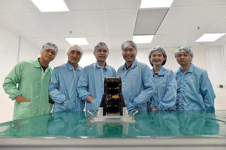 NTU Satellite Research Centre team members (from left) Richard Bui, Lim Sir Yang, Lew Jia Min, Joshua Tay, Amy Wong and Benjamin Tan with the Aoba-Velox IV nanosatellite, which will be launched in Japan later this month. They are learning from and im