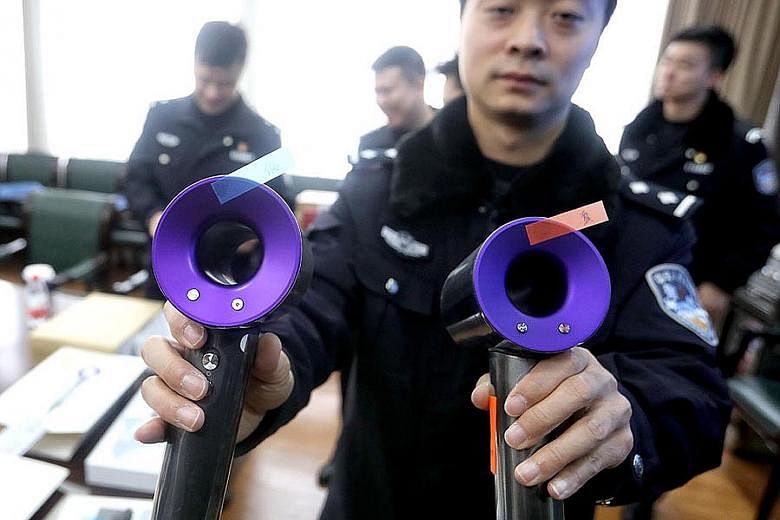 A Shanghai police officer showing a fake (left) and real Dyson hairdryer last Friday.