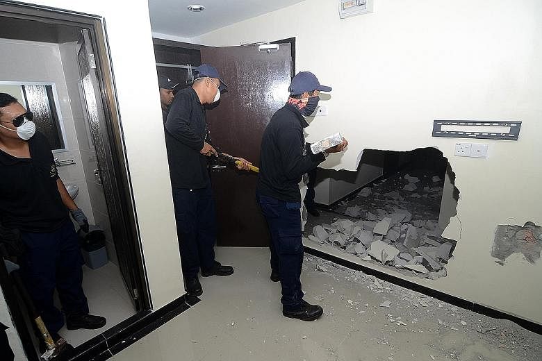 New unlicensed hotels have sprouted in George Town (above) in areas such as Love Lane. Penang Island City Council officers (below) knocking down a room in an illegal hotel in a recent operation.