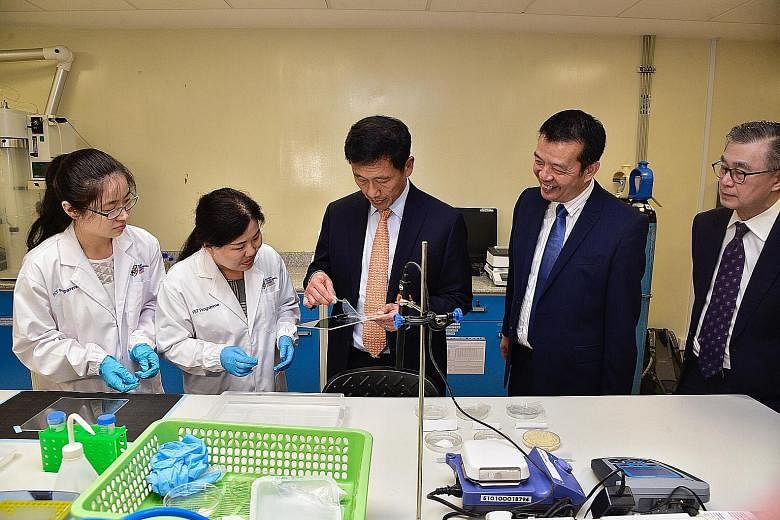 Minister for Education Ong Ye Kung (centre) examining a biodegradable cellulose film packaging in the laboratory with (from left) PhD student Cui Xi; research fellow Zhao Guili; Professor William Chen, director of NTU's Food Science and Technology pr