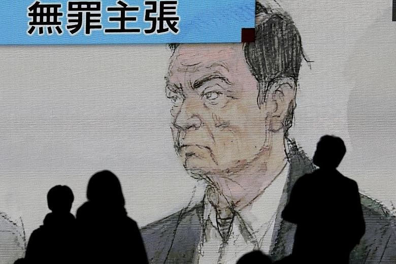Pedestrians watching a news clip featuring ousted Nissan chairman Carlos Ghosn during his court appearance in Tokyo yesterday.
