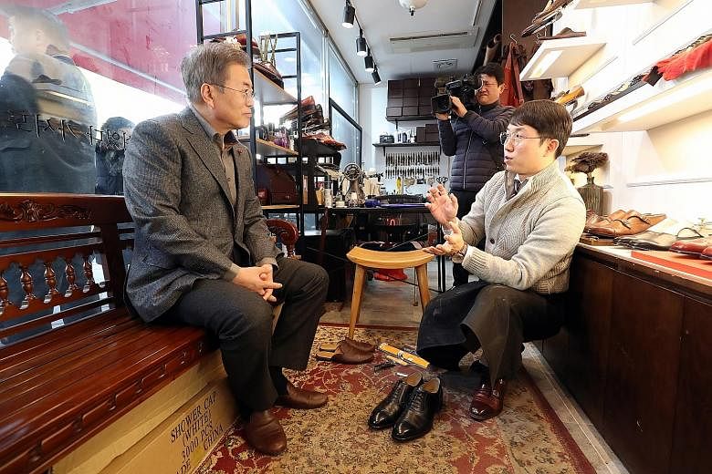 South Korean President Moon Jae-in (left) talking to the owner of a shoe shop in Seoul last week while having his shoes made. Mr Moon had pledged to be a "Gwanghwamun President" with his office in downtown Seoul instead of the secluded Blue House, to