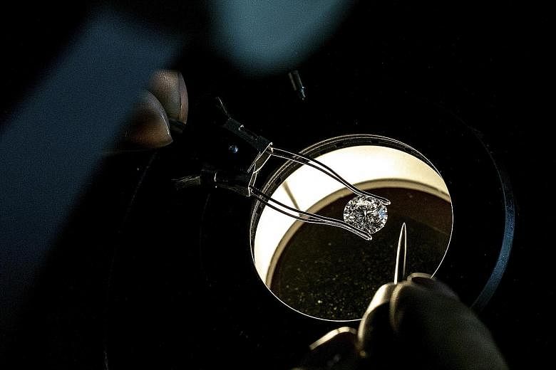 (Clockwise, from above) A specialist looks at a diamond at a Tiffany & Co facility in Pelham, New York; a specialist grades diamonds; a diamond is polished; and a diamond setter puts a diamond on a platinum band.