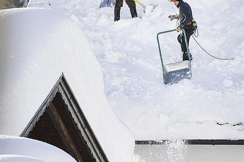 Workers clearing a roof in the town of Gerold, in Germany, following heavy snowfall.