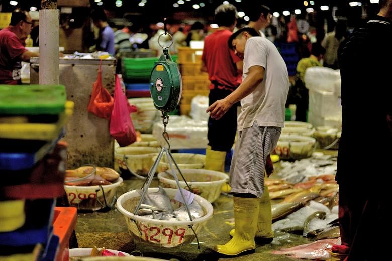 A worker weighing fish at the Jurong Fishery Port. Supermarket chain NTUC FairPrice says that the varieties of fish that are more popular during Chinese New Year, like red grouper, snapper, threadfin and pomfret, cost 10 to 15 per cent more now compa