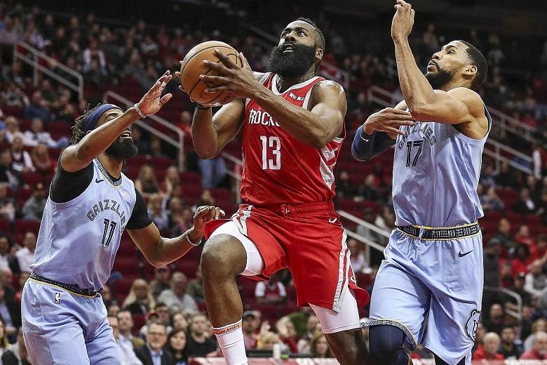 Houston Rockets guard James Harden making light of the defensive efforts of Memphis Grizzlies' Mike Conley (No. 11) and guard Garrett Temple as he drives to the basket during the Rockets' 112-94 win. Harden scored 57 points, the third game in which h