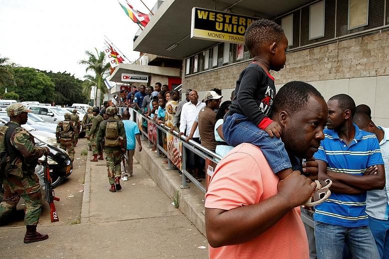 Armed soldiers patrolling the streets as people queue at a supermarket in Harare, Zimbabwe, yesterday. The capital was gripped by three days of protests after President Emmerson Mnangagwa increased the price of fuel by more than 150 per cent. Many ac