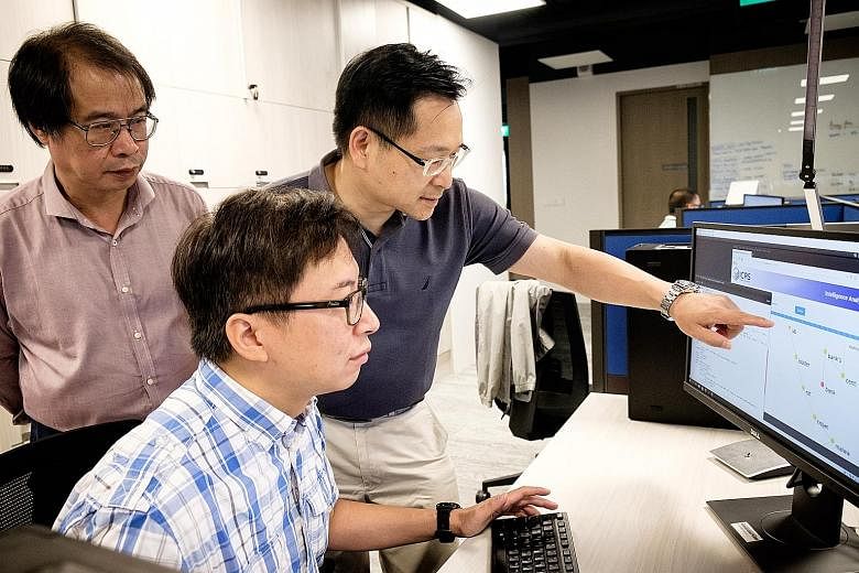 Professor Lam Kwok Yan (in dark blue), senior research engineer Dr Victor Chu (seated), and Associate Professor Wang Huaxiong from Nanyang Technological University, discussing strategies for cyber-security solutions.