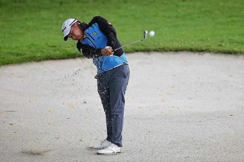 Thailand's Poom Saksansin hitting out of the bunker on the 18th hole at the rain-delayed Singapore Open at Sentosa's Serapong Course yesterday. He is looking forward to some welcome rest and chicken rice.
