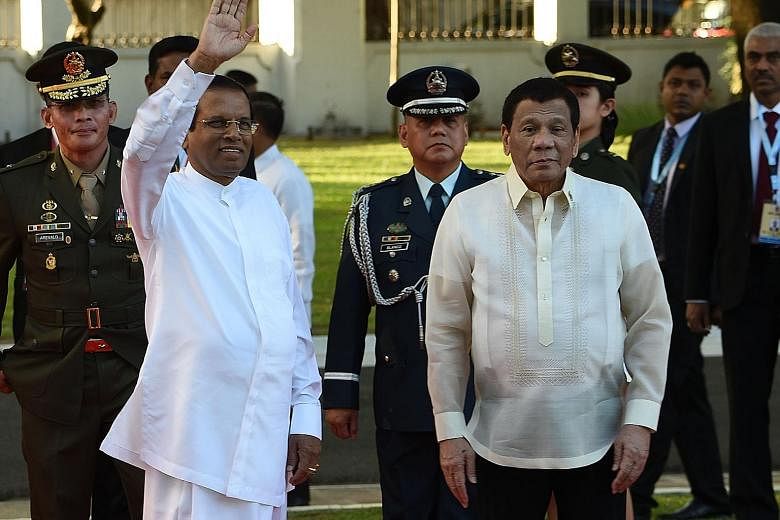 Sri Lankan President Maithripala Sirisena waving as Philippine President Rodrigo Duterte looks on after reviewing a guard of honour during a welcome ceremony at the Malacanang Palace in Manila on Wednesday.