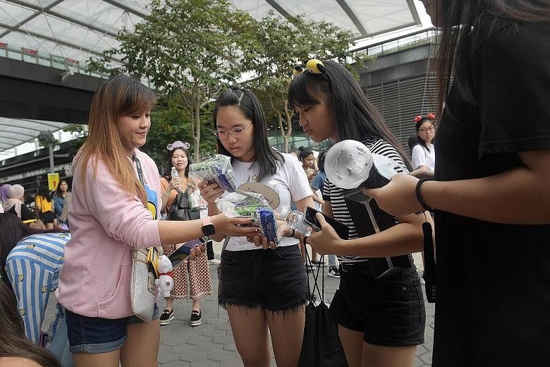 Ms Kimberly France (left) giving out snack packs to fans yesterday. She came up with the idea after she realised fans who bought mosh pit tickets would have to queue for hours before entering the concert venue.