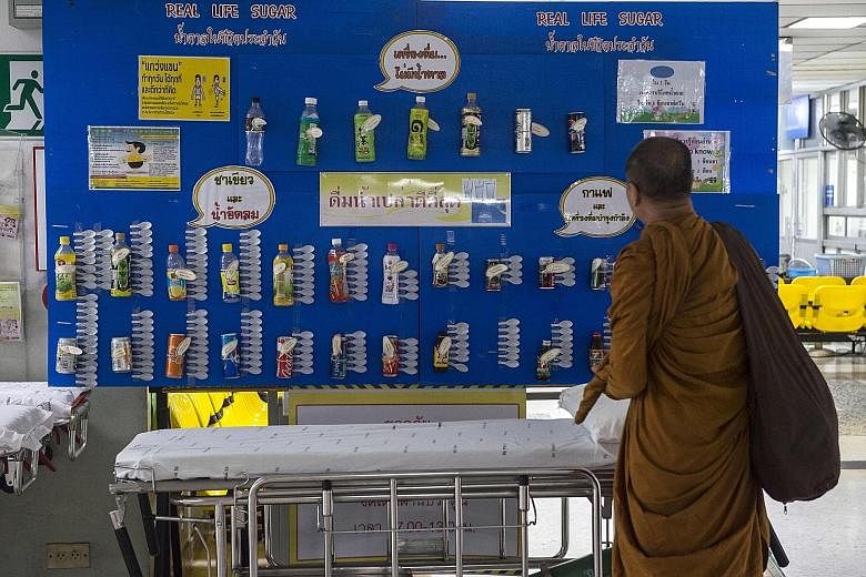 A monk checking out a display showing the sugar content of various drinks at a hospital in Bangkok. Latest available data on the website of the Office of the Cane and Sugar Board shows Thais' sugar consumption from January to September last year was 